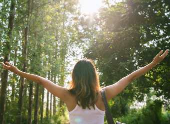 Femme dans la nature levant les bras