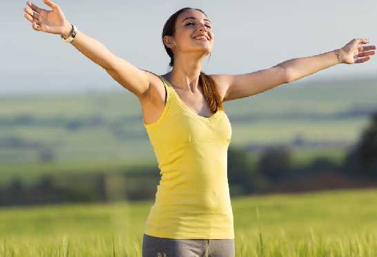 Femme aux bras ouverts rayonnante dans la nature