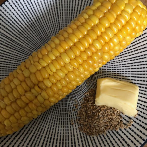 Épi de maïs, beurre et gomasio sur une assiette bon pour l'hygiène de vie du sportif